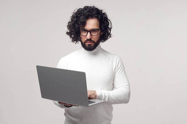 Strict man in eyeglasses typing on laptop in studio - Foto, immagini