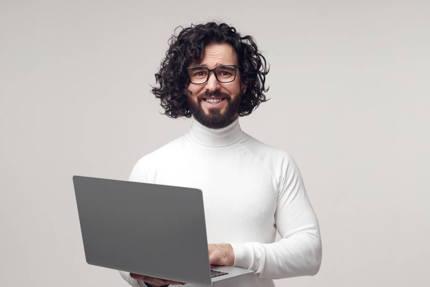 Uncertain bearded man using laptop in studio - Foto, afbeelding