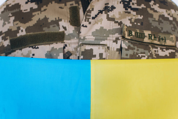 Украинский патриот в военной форме держит желто-синий флаг на белом фоне - Фото, изображение