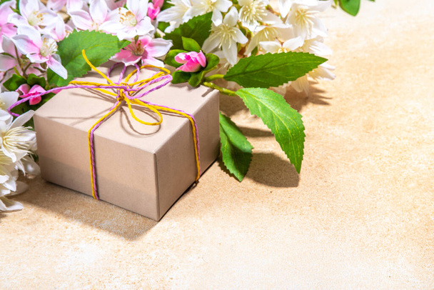 母の日のグリーティングカードの背景にプレゼントや花。お祝いのリボンとギフトボックス、タグあなたのお母さんを愛し、春の開花枝花束フラットレイコピースペース - 写真・画像