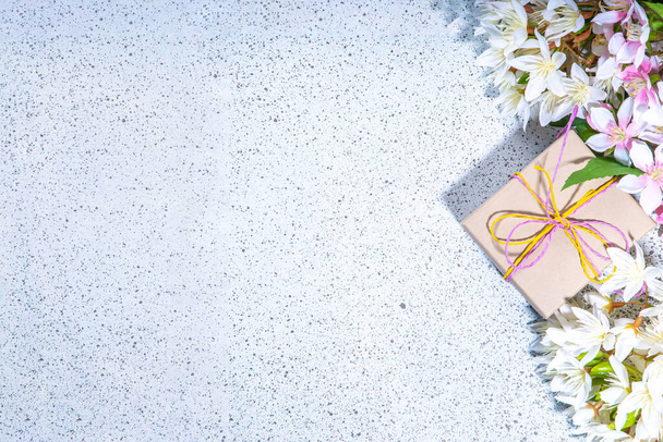 Anneler günü tebrik kartı geçmişi mevcut ve çiçekli. Şenlik kurdeleli bir hediye kutusu, "Seni seviyorum anne" etiketi, bahar çiçekleri açan dallar buket düz bir kopya alanı - Fotoğraf, Görsel