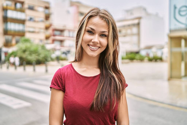 Junges kaukasisches Mädchen lächelt glücklich in der Stadt. - Foto, Bild