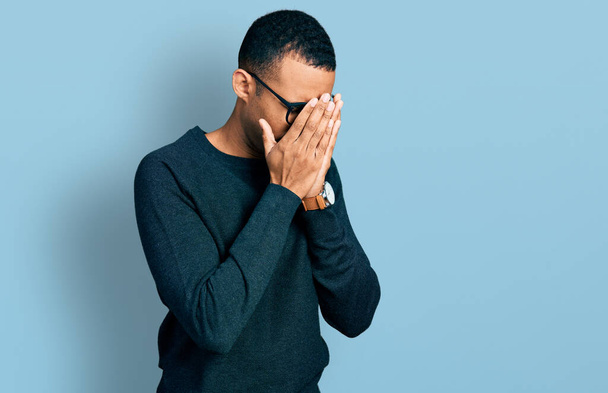 Young african american man wearing casual clothes and glasses with sad expression covering face with hands while crying. depression concept.  - Photo, Image