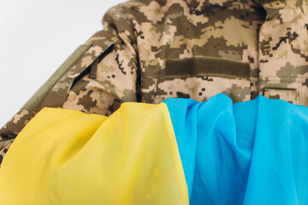 軍の制服を着た感情的な若い髭を生やしたウクライナの愛国者兵士の肖像画がオフィスで旗を掲げている - 写真・画像