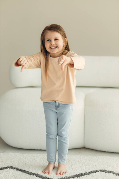 portrait of a cute smiling little girl at home. girl shows like - Valokuva, kuva
