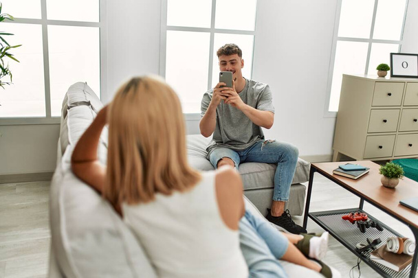 Ο άνθρωπος κάνει φωτογραφία στην κοπέλα του χρησιμοποιώντας smartphone στο σπίτι. - Φωτογραφία, εικόνα