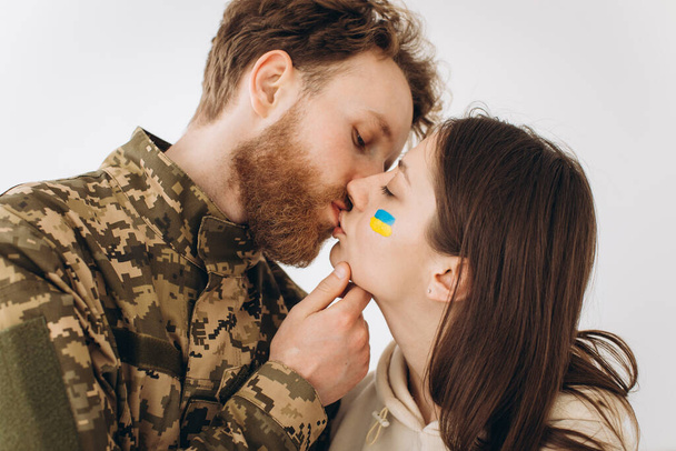 Couple ukrainien, militaire barbu homme en uniforme embrasse sa petite amie à la maison - Photo, image