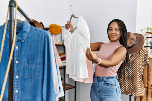 Jeune femme afro-américaine souriant achats confiants au magasin de vêtements - Photo, image