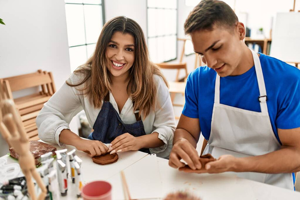Due studenti sorridenti felice modellazione argilla seduto sul tavolo a scuola d'arte. - Foto, immagini