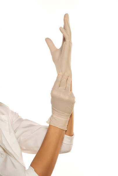Mãos de mulher que põem luvas de látex em um fundo branco - Foto, Imagem