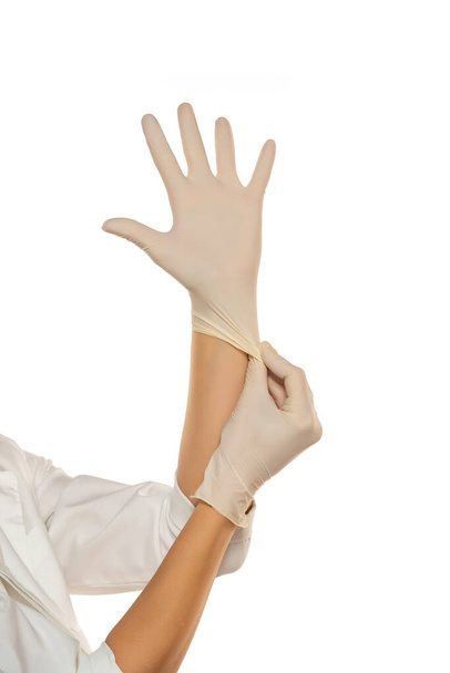 Manos de mujer poniéndose guantes de látex sobre fondo blanco - Foto, imagen