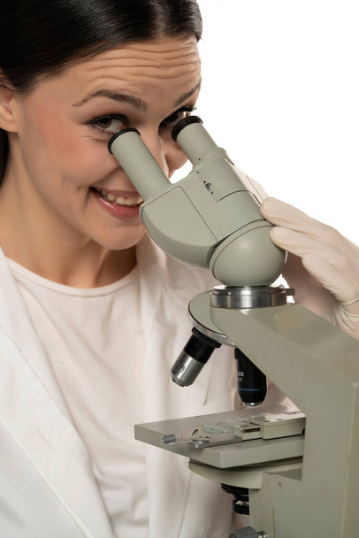 顕微鏡を通して見る幸せな女性科学者は白い背景を閉じて - 写真・画像