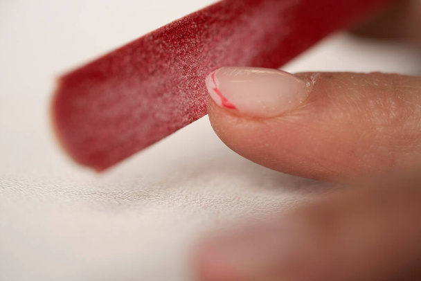 El proceso de limar las uñas. Cortando francés rojo. Manicura femenina de cerca - Foto, imagen