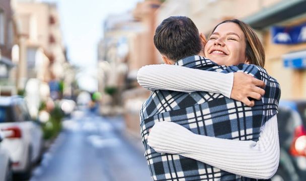 Young man and woman couple hugging each other standing at street - Foto, Imagen