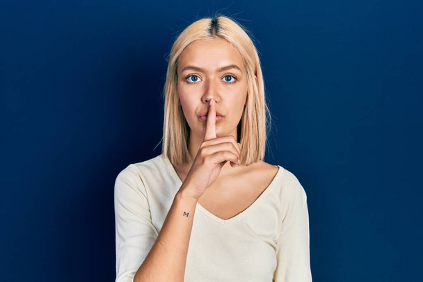 Beautiful blonde woman wearing casual sweater asking to be quiet with finger on lips. silence and secret concept.  - Foto, Imagen