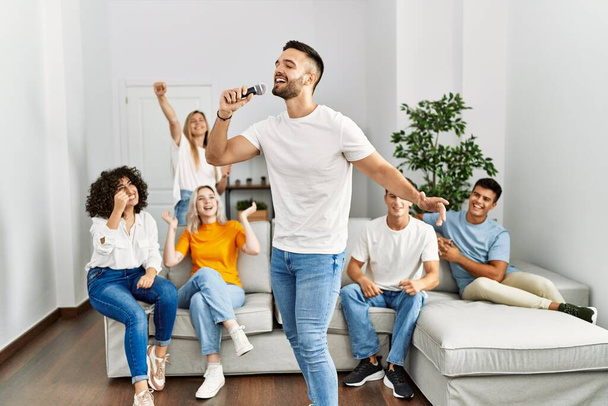 Group of young friends having party singing song using microphone at home. - Photo, Image