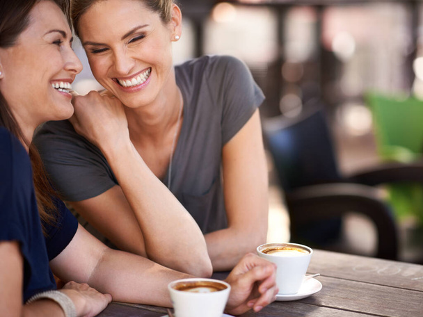 I wtedy nie uwierzysz, co powiedział. Ujęcie dwóch atrakcyjnych kobiet śmiejących się podczas picia kawy. - Zdjęcie, obraz