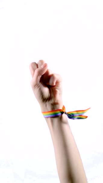 Hand wearing a bracelet with the colors of the LGBT flag showing three fingers. Vertical video. - Footage, Video