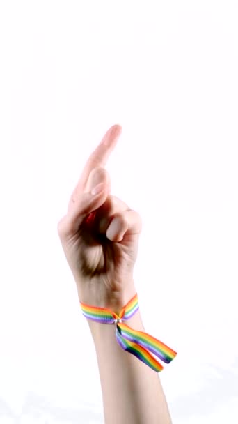 Mano usando una pulsera con los colores de la bandera LGBT negando con su dedo. Diciendo que no. Símbolo LGBT. Vídeo vertical. - Metraje, vídeo