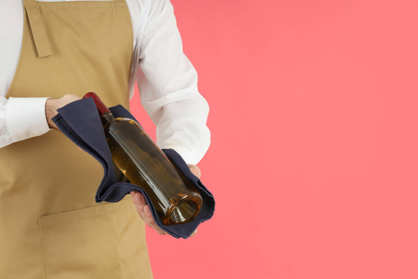 Homem garçom segura garrafa de vinho no fundo rosa - Foto, Imagem