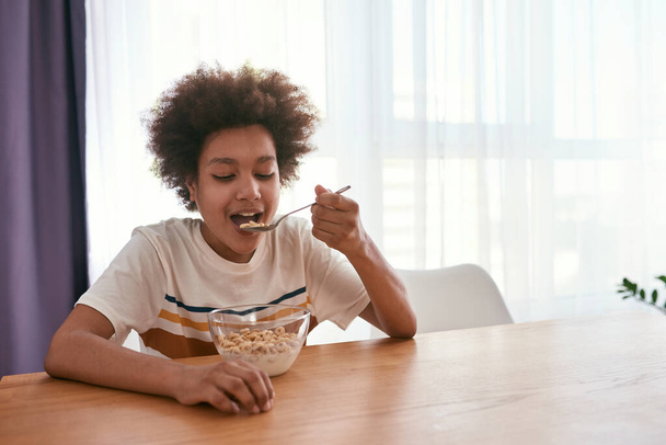 Curly black boy eating cereals at table at home - Foto, Imagem