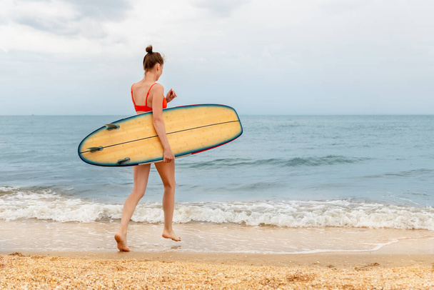 Vista lateral del perfil joven adulto delgado deportivo chica surfista disfrutar de divertirse nadando tabla de surf mar costa ola agua clara día soleado. Deporte sano despreocupado hobby estilo de vida concepto de vacaciones - Foto, imagen