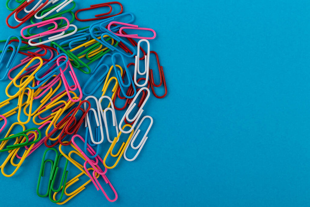Colored paper clips. Colored paper clips macro close up isolated on a blue background with copy space. - Fotó, kép