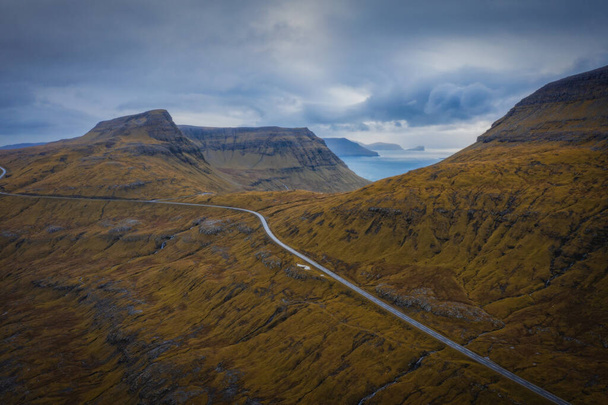 Aerial view on serpentine road on the island Streymoy near the village Nordradalur with view of Koltur island. Faroe Islands, Denmark. November 2021. Lonely wanderer on serpentine road - Photo, Image
