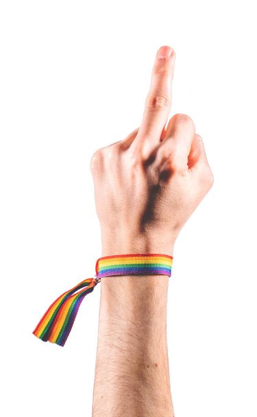 Mano con un brazalete con los colores de la bandera LGBT mostrando el dedo medio como símbolo de protesta. Símbolo LGBT. - Foto, imagen