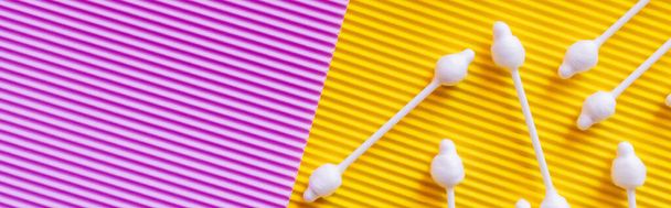 top view of ear sticks on yellow and violet textured background, banner - 写真・画像
