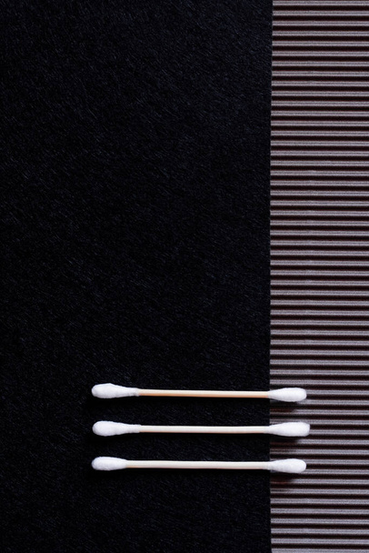 top view of two cotton ear sticks on black and textured background with copy space - Fotoğraf, Görsel
