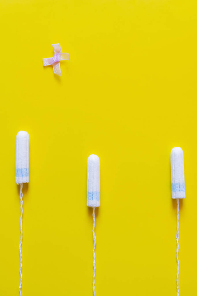 top view of bow near hygienic tampons on bright yellow background - Zdjęcie, obraz