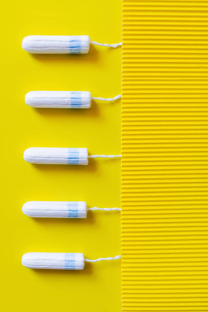 top view of vertical row of tampons on yellow and textured background - 写真・画像