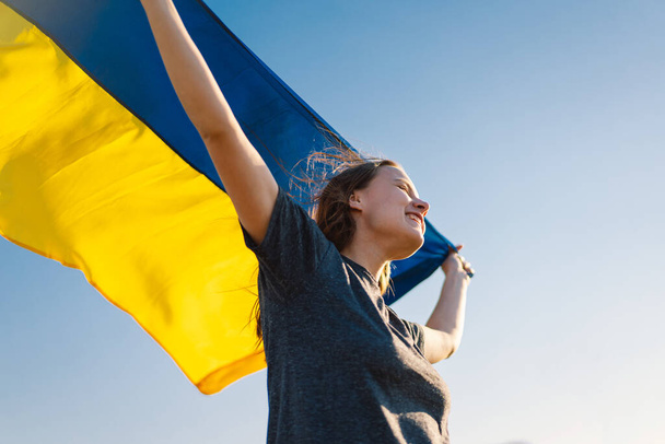 Mujer sosteniendo una bandera amarilla y azul de Ucrania al aire libre - Foto, imagen