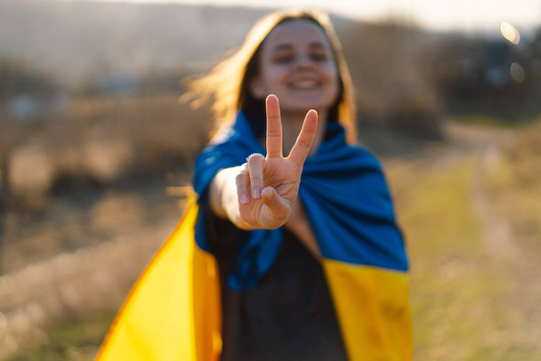 Fröhliches ukrainisches Mädchen, das ein Zeichen des Friedens oder Sieges zeigt. - Foto, Bild