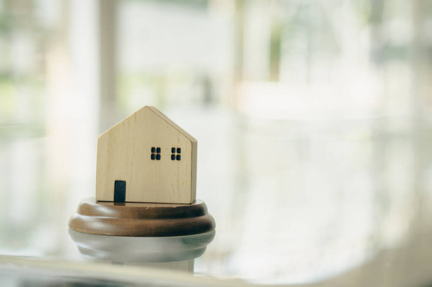 ενός μικρού ξύλινου μοντέλου σπιτιού με το θολό φόντο για την ιδιοκτησία κατοικίας ή ιδέες ακινήτων που λαμβάνονται μπροστά. Φτιαγμένο με vintage χρώμα φίλτρου. - Φωτογραφία, εικόνα