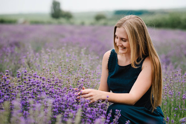 Beautiful girl in dress in purple lavender field. Beautiful woman walk on the lavender field on sunset. Enjoy the floral glade, summer nature. Nature cosmetics concept make-up. - Valokuva, kuva