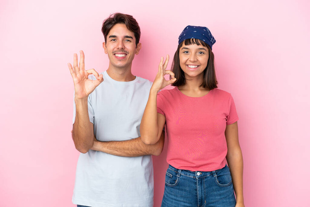 Νεαρό ζευγάρι απομονώνονται σε ροζ φόντο δείχνει μια πινακίδα εντάξει με τα δάχτυλα - Φωτογραφία, εικόνα