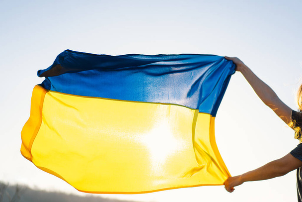 Woman holding a yellow and blue flag of Ukraine in outdoors - Фото, зображення