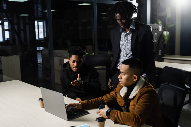 Teamwork online mit Laptop. Schwarzafrikanische und asiatische Kollegen. 3 multiethnische Geschäftsleute sehen Videokonferenz mit Kollegen und Arbeitgeber - Foto, Bild