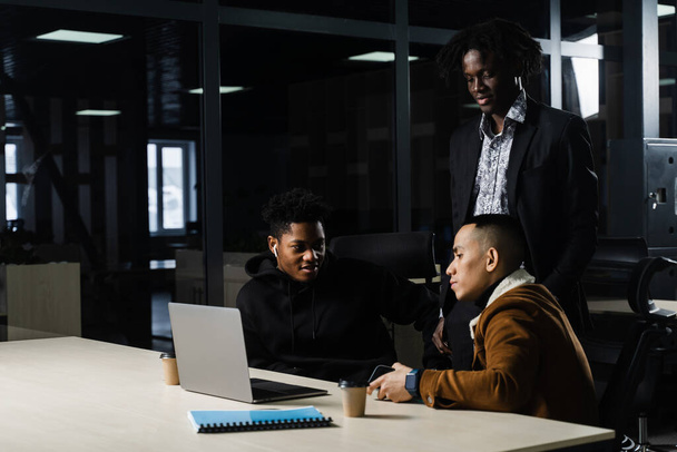 ブリーフィングルームでプロジェクトにオンラインで取り組んでいる同僚の多国籍ブレインストーミンググループ。黒人アフリカ人のビジネスマンとアジア人の仕事がチームで - 写真・画像