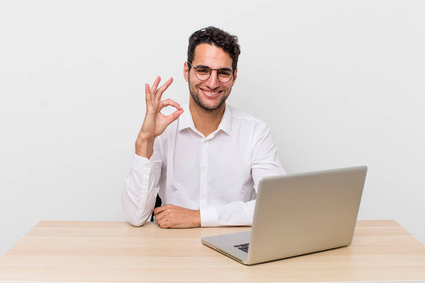 hispánský pohledný muž, který se cítí šťastný, projevuje souhlas s povolným gestem. podnikatelský a kancelářský koncept - Fotografie, Obrázek