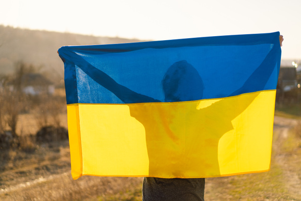 女性は屋外でウクライナの黄色と青のフラグを保持 - 写真・画像