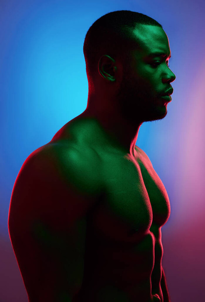 Challenges only make you stronger. Studio shot of a man posing shirtless against a neon background. - Fotó, kép