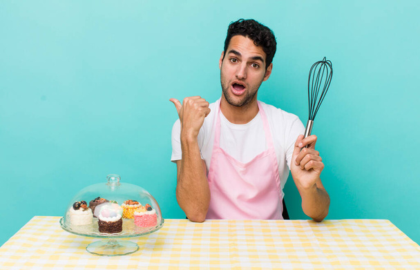 hispanic handsome man looking astonished in disbelief. home made cakes cocnept - 写真・画像