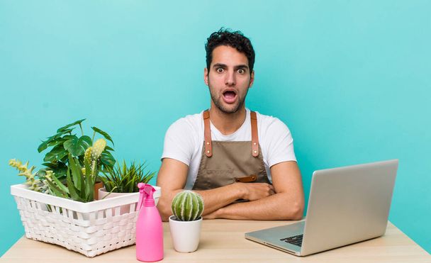 hispanic handsome man looking very shocked or surprised. garden and plants concept - 写真・画像