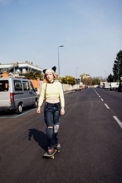 rebel aternative young woman outdoors riding skate skateboarding empty city streets - Фото, изображение
