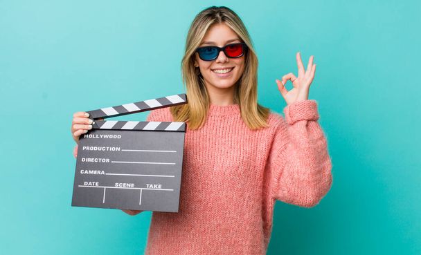 pretty blonde woman feeling happy, showing approval with okay gesture. cinema concept - Foto, afbeelding