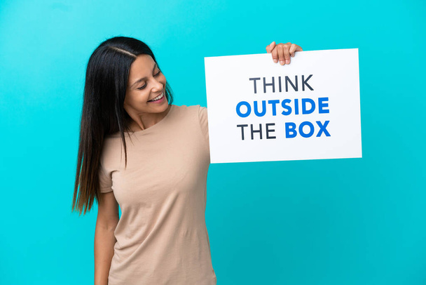 Mujer joven sobre fondo aislado sosteniendo una pancarta con texto Think Outside The Box - Foto, imagen