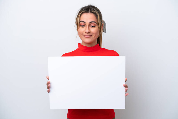 Young caucasian woman isolated on white background holding an empty placard and looking it - Фото, изображение
